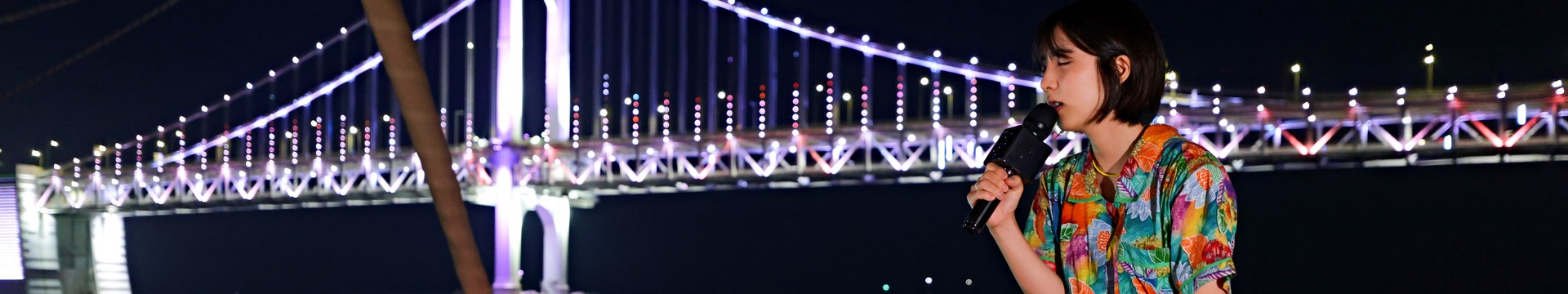以广安大桥为背景，在游艇船头唱歌的街头艺人