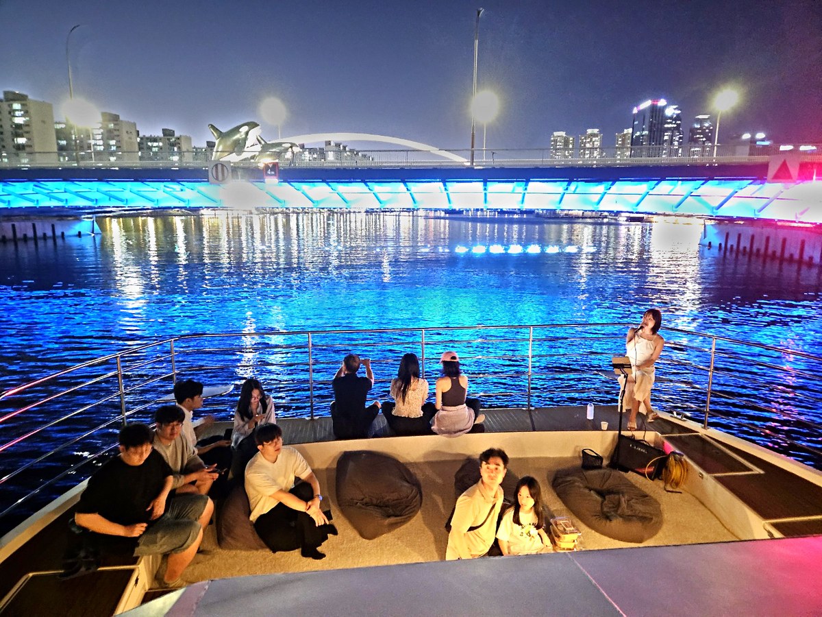 无人机秀上演时,夜海上船头甲板的团体游客