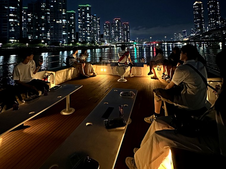 以夜景为背景聚在甲板上的团体游客